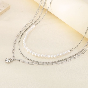 Detail of layered stainless steel necklace featuring elegant pearls and a silver heart pendant
