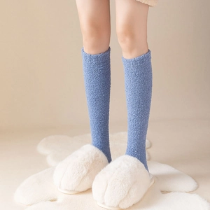 Blue coral fleece knee-high socks paired with white cat paw plush slippers on a rug