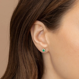 Close-up of a vintage round emerald stud earring with a sparkling zircon halo on ear