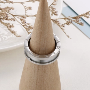 Detailed view of silver ring featuring Roman numeral engravings on a wood display stand