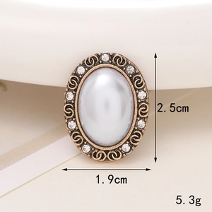 Detailed view of vintage oval pearl charm with gold filigree and tiny white rhinestones