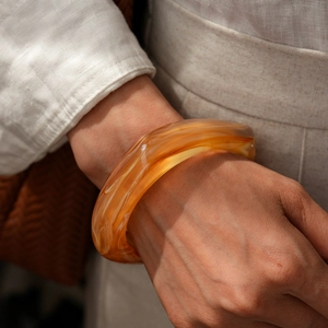 Close-up of amber marble resin bangle showing natural fluid textures on female wrist