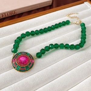 Detailed shot of retro gold necklace with green beads and a pink gemstone pendant