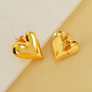 Macro shot of 3D heart-shaped gold studs featuring mirror polished finish and details