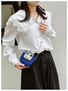 Close-up of blue mini leather bag with silver chain strap worn by a model in casual outfit