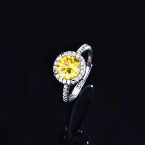 Halo set round yellow gemstone ring in silver finish with pavé diamonds on black mirror