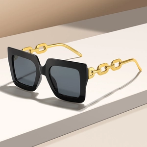Primer plano de gafas de sol cuadradas con patillas de cadena metálica dorada