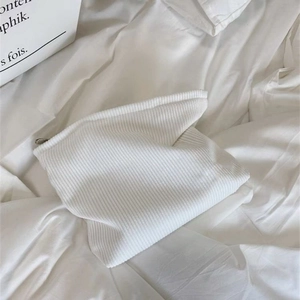 Close-up of a white corduroy cosmetic bag with a zipper on a white textured background