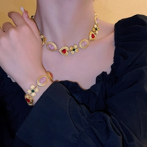 Detail of vintage gold necklace with pink cameo and red heart gemstone on model