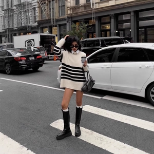 Chic black and white striped oversized turtleneck sweater paired with long leather boots