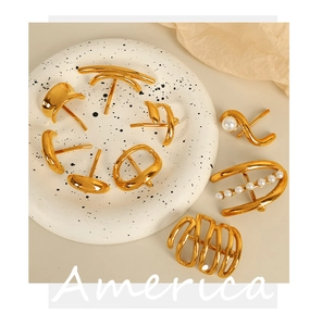 Detail of gold geometric earrings with pearl accents on a white speckled plate