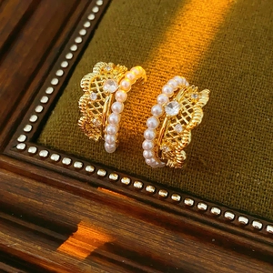 Macro detail of gold-plated lace hoop earring with white pearls and sparkling zircons
