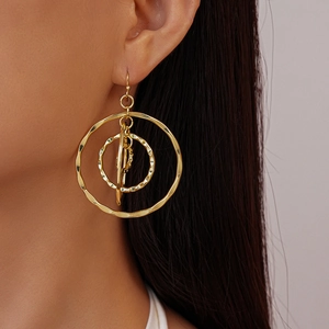 Close-up of golden multi-layer circular hollow earrings on model showing metal texture