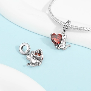 Macro shot of 925 silver cat charm holding a red heart gemstone with 5925 hallmark