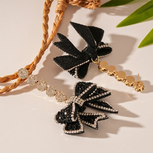 Macro detail of dark velvet bow earrings with shimmering rhinestones and golden tassels