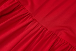 Macro view of pleated fabric texture and craftsmanship on a red backless jumpsuit