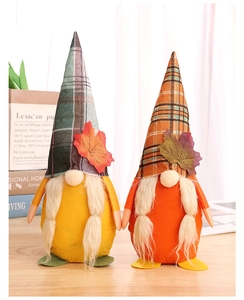 Close-up of fall gnomes with maple leaf decorations on a wooden table in warm light