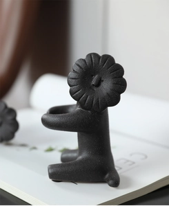 Macro detail of black matte ceramic lion sculpture with a floral head and storage tray