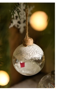 Detail of an 8cm glass Christmas ball with white snowflake coating and hanging rope
