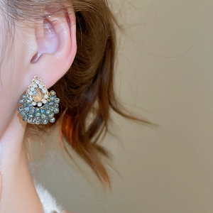Détail de boucles d'oreilles cristal champagne en goutte avec perles bleu-gris