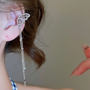 Macro shot of cubic zirconia butterfly ear cuff with shimmering chain tassels on model