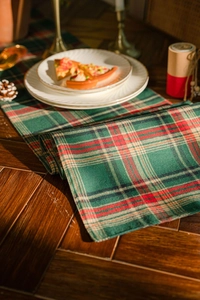Detailed close-up of red and green plaid fabric runner in a festive table setting