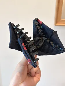 Détail d'une grande pince à cheveux avec nœud en denim vintage et broderie florale
