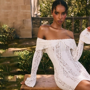 Detail of white lace off-shoulder dress with long sleeves and front lace-up design