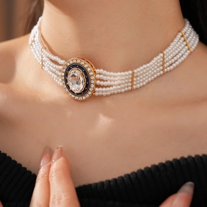 Close-up of layered pearl necklace with gold-framed diamond pendant on model neck