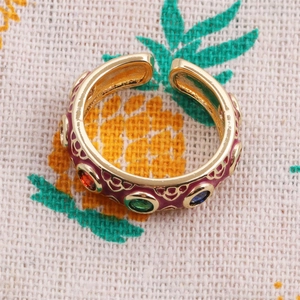 Detailed close-up of gold-plated ring with purple enamel and colorful gemstones