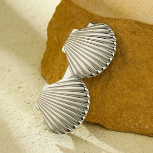 Detailed macro shot of silver scallop shell earrings on natural stone background