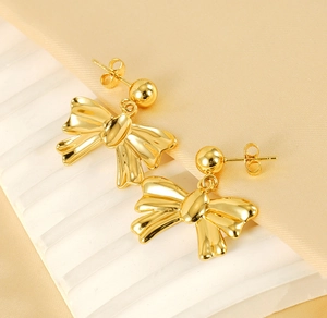 Detailed macro view of 18k gold plated bow earrings with a polished mirror finish