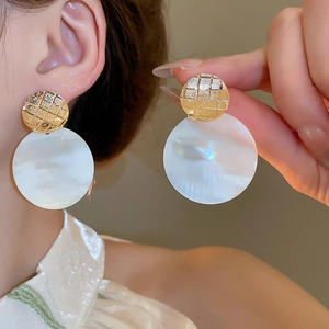 Dettaglio degli orecchini a cuore placcati oro 24k con madreperla indossati sull'orecchio