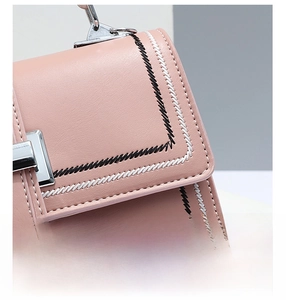 Close-up of pink crossbody bag featuring black and white zigzag embroidered edge detailing