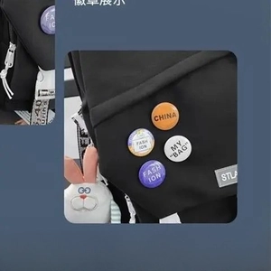 Detail of black canvas backpack featuring colorful badges and cute white plush rabbit charm