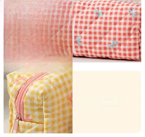 Detail of red and yellow plaid quilted cosmetic bag showing stitching and zipper texture