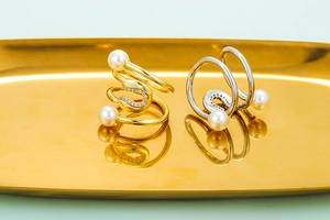 Doppellagige geometrische Ringe mit Perlen und Zirkon auf goldenem Präsentiertablett