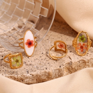 Detail of 18K gold-plated hammered texture rings with dried flowers in resin