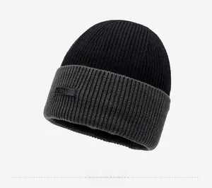 Close-up of black and grey knit beanie with leather patch and fine vertical stripes