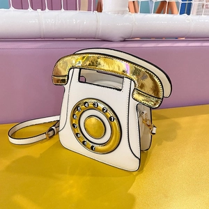 Close-up of retro pearl white telephone crossbody bag with gold dial and receiver details