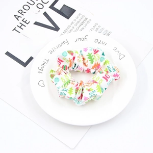 Close-up of white Christmas scrunchie with colorful holiday patterns and festive words