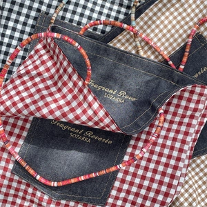 Detail of checkered canvas tote bag featuring denim patchwork and colorful beaded handles