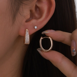 Elegant rose gold geometric oval earrings with white pavé zircons worn by a model
