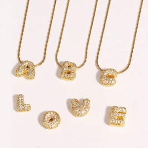 Détails des pendentifs lettres en plaqué or avec zircons sur un fond blanc neutre