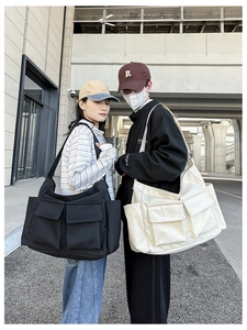 Detail of oversized canvas messenger bags with multi-pocket design in black and beige
