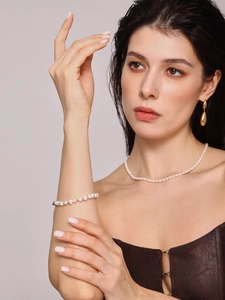 Gros plan sur un ensemble collier, bracelet en perles d'eau douce baroques et boucles dorées