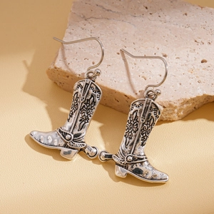Dettaglio di orecchini vintage a stivale da cowboy in argento con incisioni floreali
