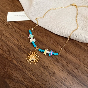 Detail of bohemian gold sun pendant necklace with colorful beads and shells on linen fabric