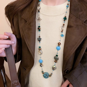 Macro shot of long beaded necklace with blue and brown resin beads and butterfly charms