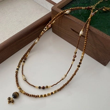 Close-up of double-layered beaded necklace with tiger eye stones on walnut wooden box